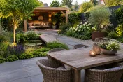Tuin met houten eettafel, rotan stoelen, vijver, pad en overdekt loungehoekje